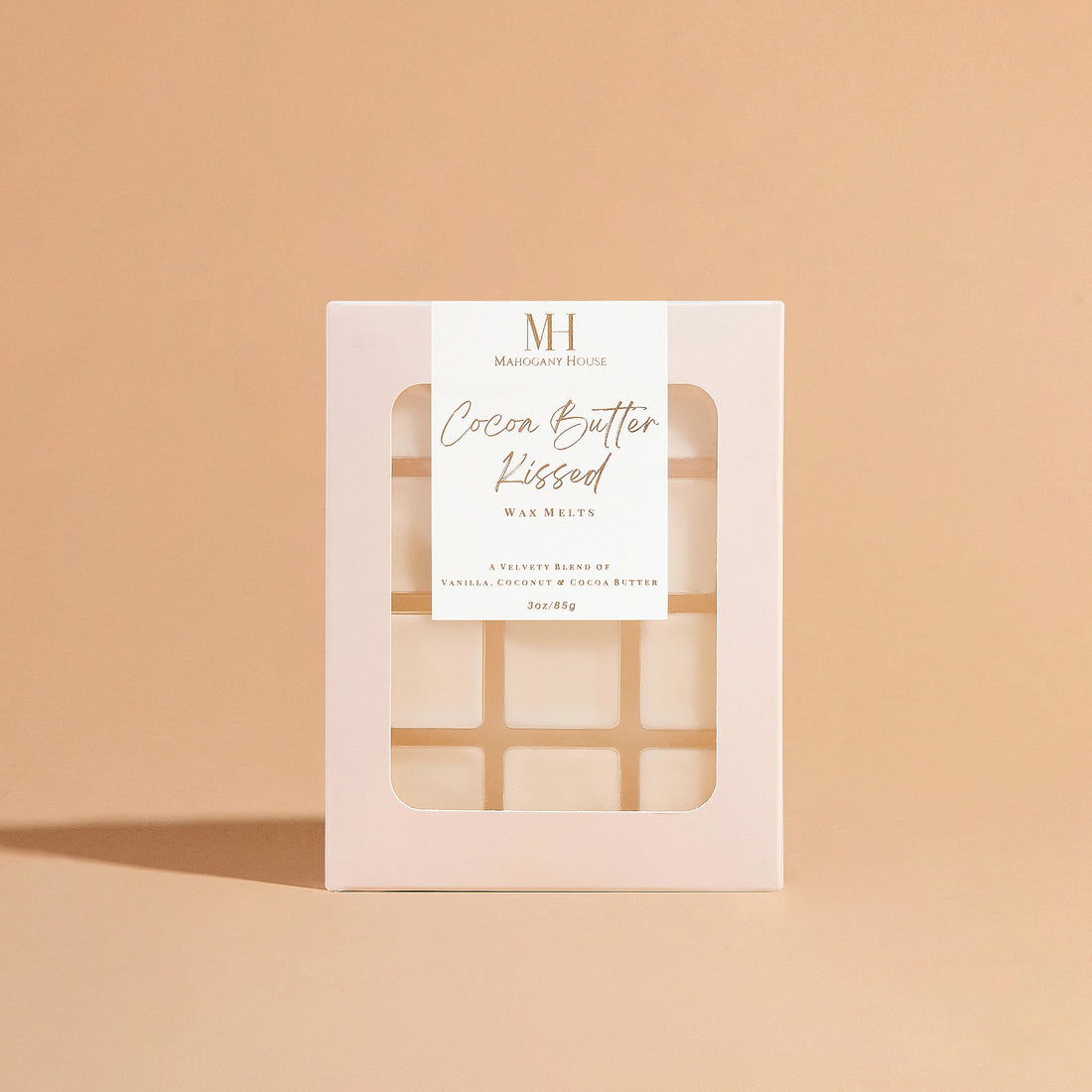 Mahogany House Cocoa Butter Kissed Wax Melt packaging displayed against a soft beige background. This hand-poured wax melt offers a creamy, warm blend of cocoa butter and subtle vanilla, creating a luxurious and cozy flameless fragrance perfect for relaxation and home ambiance.