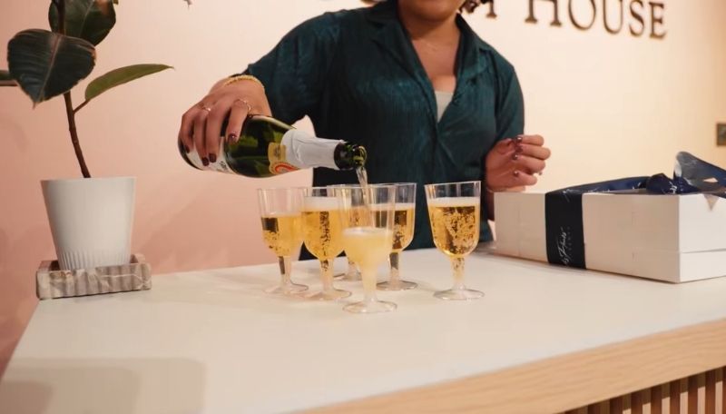 Person pouring champagne into glasses prior to a champagne toast at a candle making class.