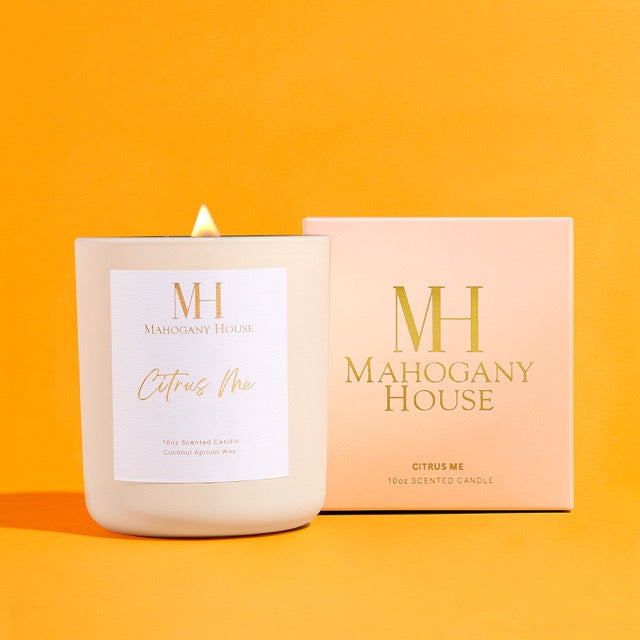 Citrus Me 10oz luxury wooden wick candle in white glass vessel with Mahogany House packaging, styled on a vibrant orange background.