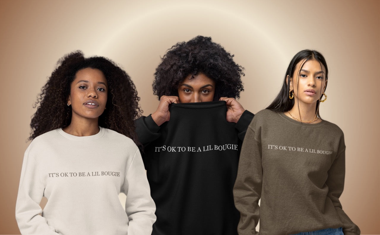 Three women wearing Mahogany House “It’s OK to Be a Lil Bougie” oversized crewneck sweatshirts in beige, black, and brown