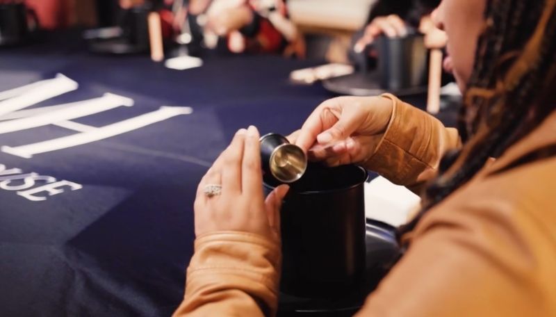 Person picking up the tools needed for a candle making class from on a black container with a blurred background