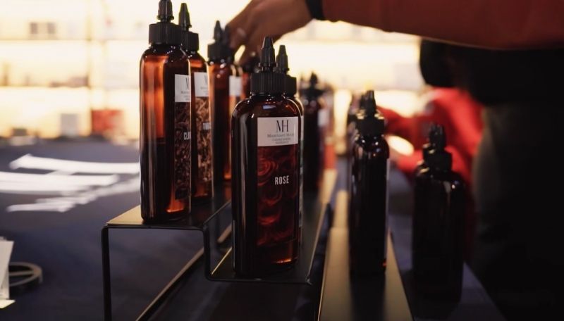 Row of dark fragrance oil bottles with labels on a table, blurred background