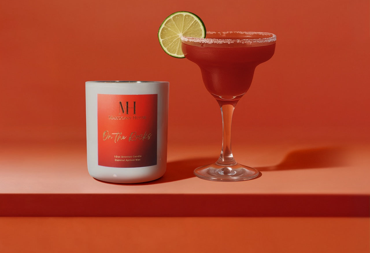 On The Rocks 10oz wooden wick candle styled with a margarita cocktail glass, fresh lime slice garnish, and bold red background.
